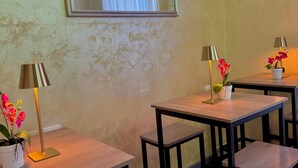 A room with a large mirror, two tables with lamps and flowers, and a decorative wall piece. - Hotel Fiorella Milano (Milan)