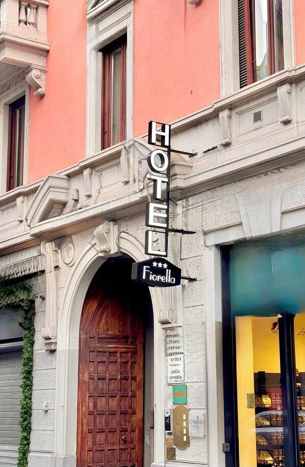 A hotel sign with a classic design and a wooden door. - Hotel Fiorella Milano (Milan)