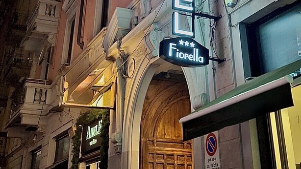 A hotel named "Hotel Fiorello" with a classic architectural style, featuring ornate balconies and a prominent neon sign. - Hotel Fiorella Milano (Milan)