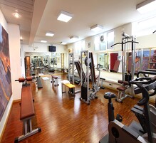 Una palestra con diverse attrezzature per esercizi, una panca e un muro con specchi.