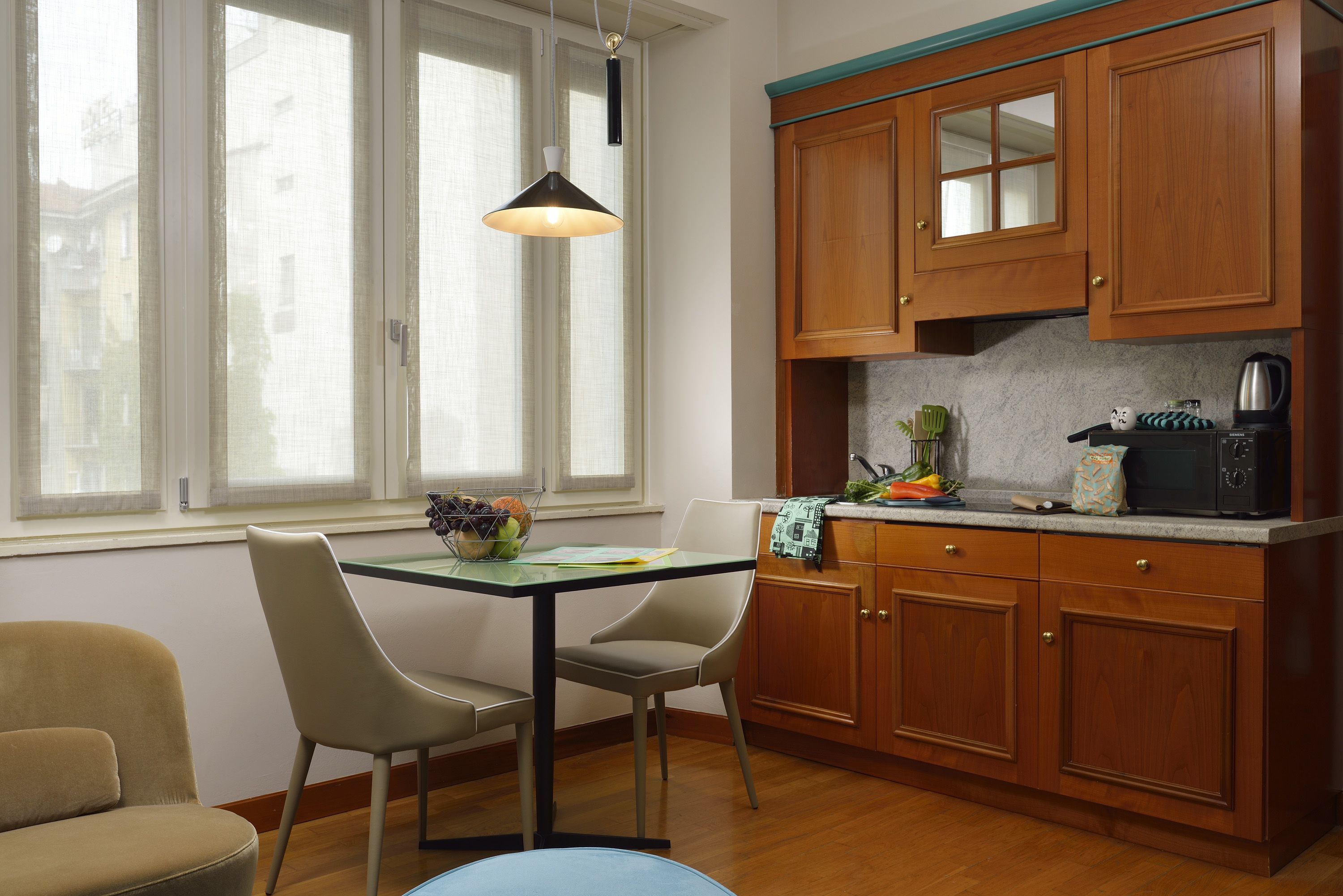 A kitchen with wooden cabinets, a dining table with chairs, and a window with curtains.