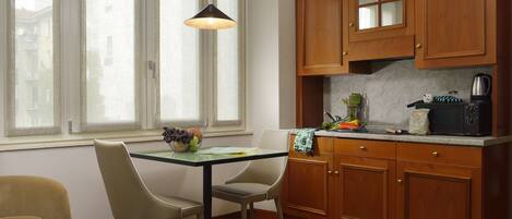 Una cocina con armarios de madera, una mesa de comedor con sillas y una ventana con cortinas.