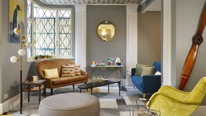 Ein Wohnzimmer mit einem braunen Sofa, einem blauen Sessel, einem gelben Sessel, einem Couchtisch und einem runden Hocker.