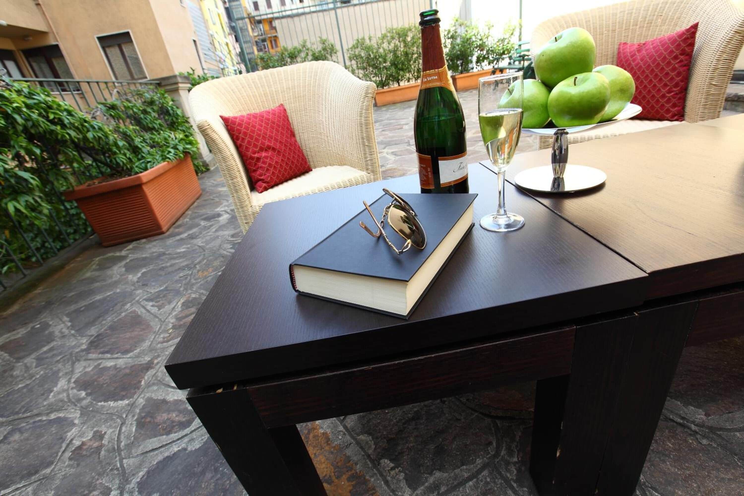 A table with a book, a bottle of champagne, a glass of champagne, and green apples.