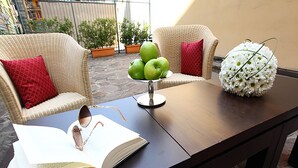 Ein Holztisch mit einem Buch, einer Brille und einer Vase mit weißen Blumen.