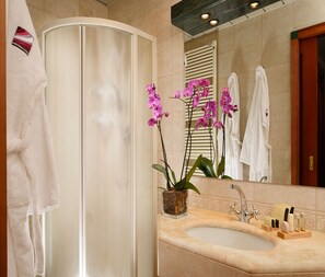 A bathroom with a white bathtub, a sink with toiletries, and pink orchids. - Residenza delle Città (Milan)