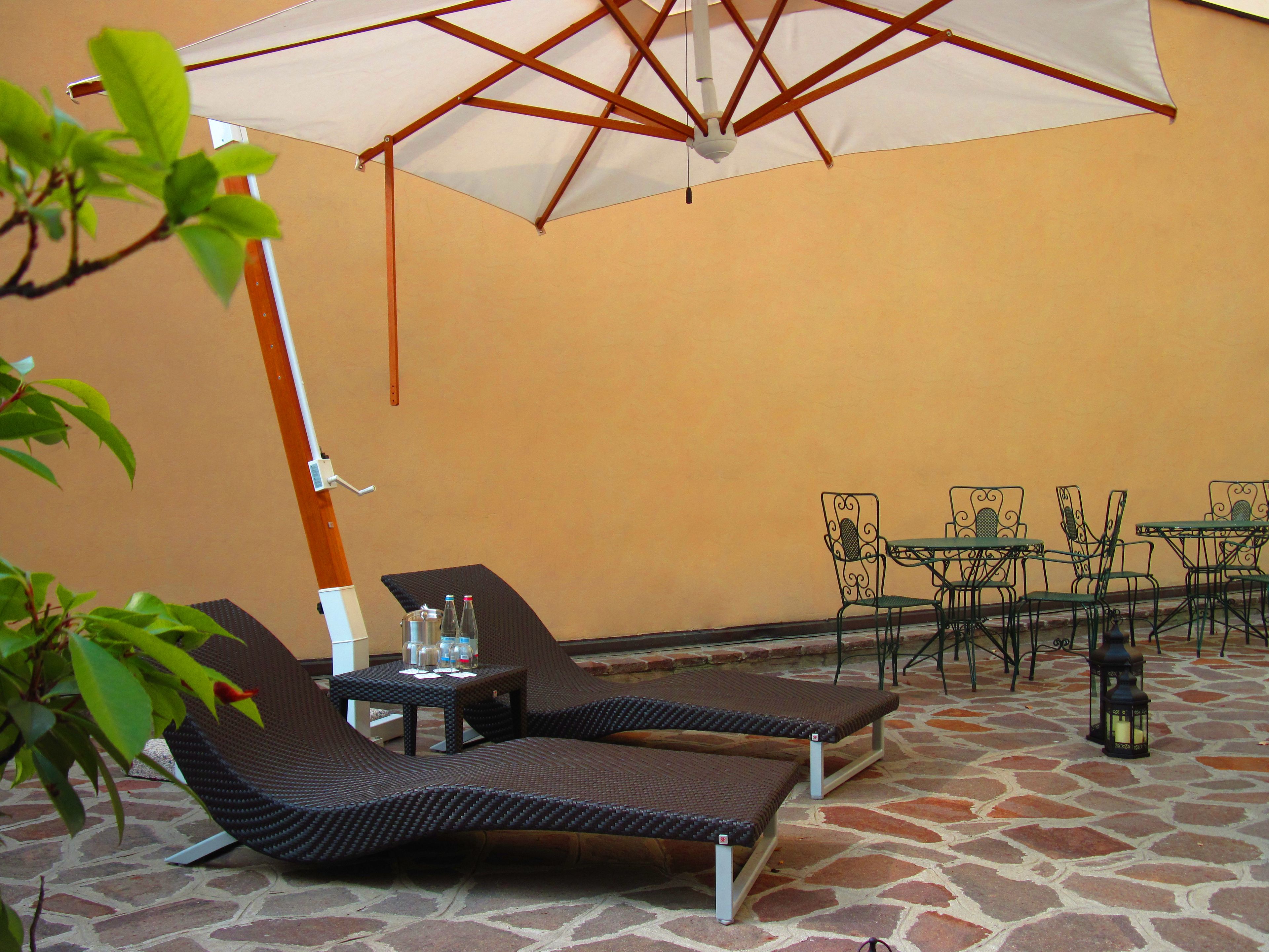 Un espace patio comprenant deux chaises longues, une table et un parasol.