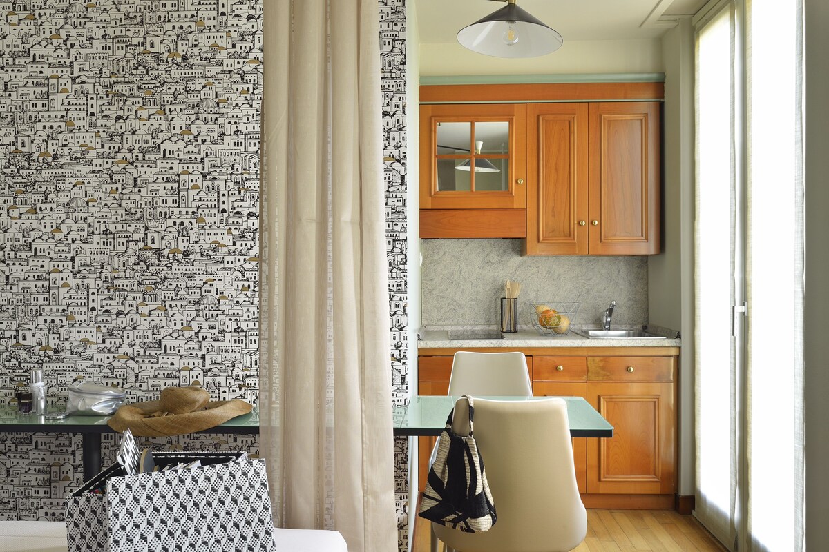 A kitchen with wooden cabinets, a marble countertop, and a hanging light fixture.