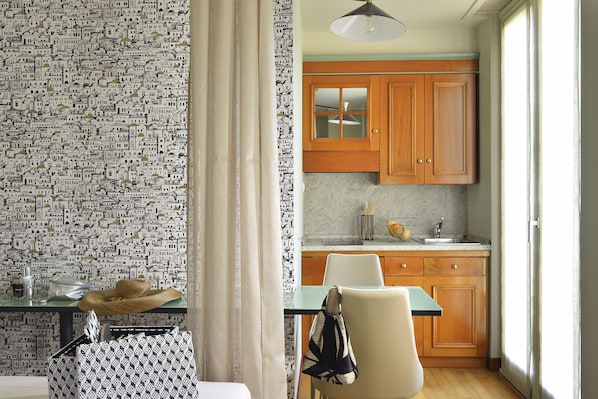A kitchen with wooden cabinets, a marble countertop, and a hanging light fixture.