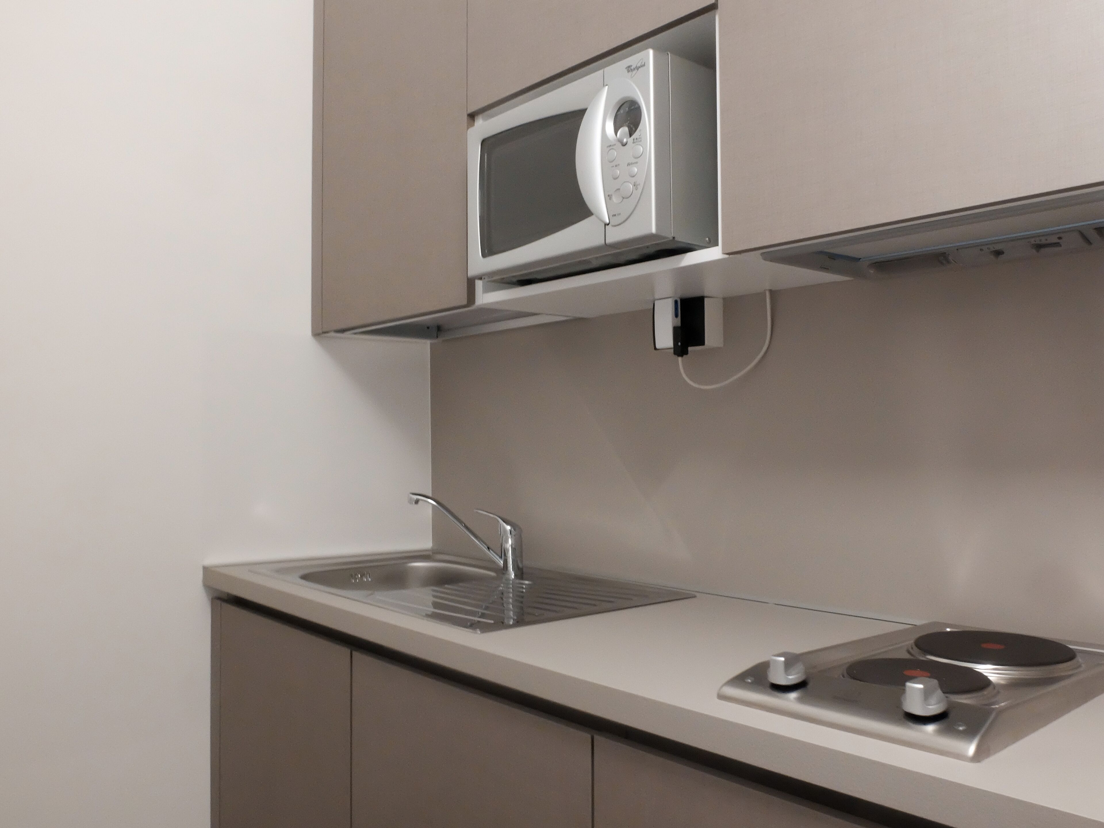 Una cucina con forno a microonde integrato, lavello e piano cottura.