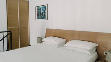 A hotel room with a bed, a wooden headboard, a bedside lamp, a nightstand, and a wardrobe.