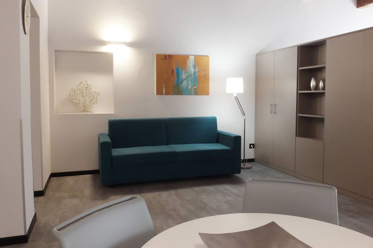 Un salon moderne avec un canapé turquoise, une table ronde blanche et un lampadaire.