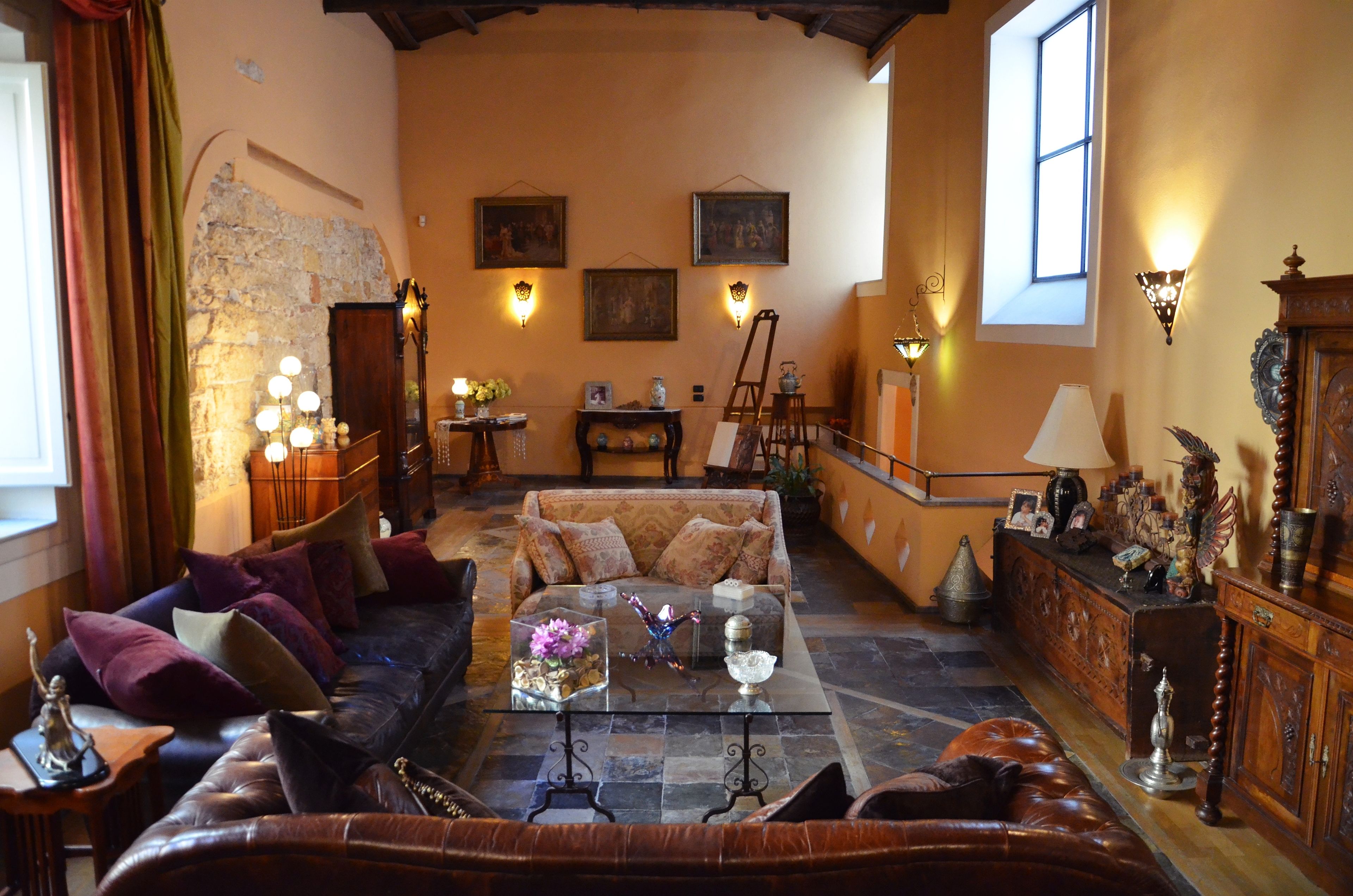 Ein gemütliches Wohnzimmer mit einer Couch, einem Couchtisch und einem Kamin. Wandleuchten und ein Fenster sorgen für natürliches Licht.