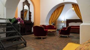 A room with a checkered floor, red velvet sofas, a wooden cabinet, and a mirror.