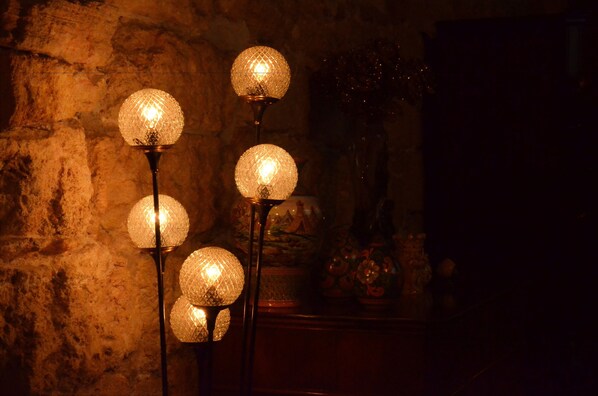 A series of spherical lamps with a textured surface, mounted on a stand against a stone wall background.