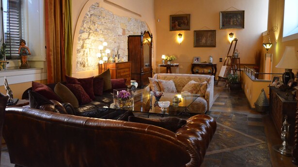 Una sala de estar acogedora con una pared de piedra, un sofá de cuero y una mesa de centro de vidrio con objetos decorativos.