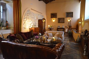 A cozy living room with a stone wall, leather sofa, and a glass coffee table with decorative items. - Ai Cartari (Palermo)