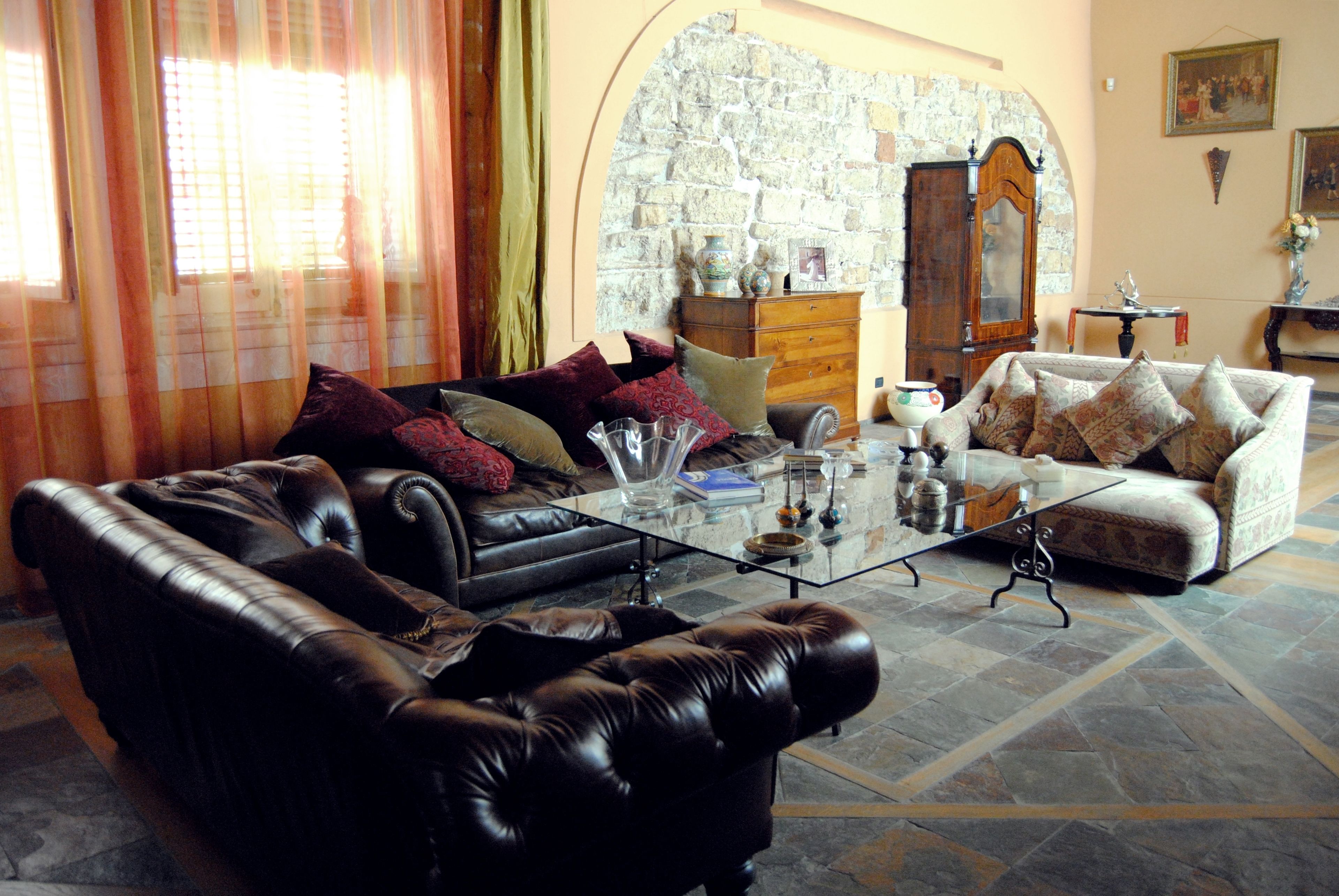 A living room with a leather sofa, a glass coffee table, and a patterned armchair.