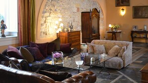 Un salón acogedor con pared de piedra, vigas de madera en el techo y una chimenea. Hay dos sofás y una mesa de centro con adornos.