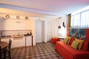Kompakti oleskelutila, jossa on keittiö, ruokailualue ja sohva tyynyineen.