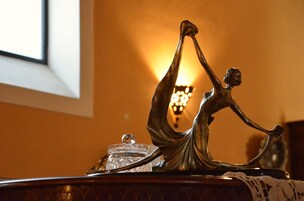 Una statua in bronzo raffigura una donna in una posa dinamica su un tavolo.