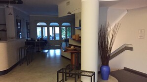 A spacious lobby with a central column, a staircase, and a seating area with a small table and chairs. - Albergo della Corona (Binasco)