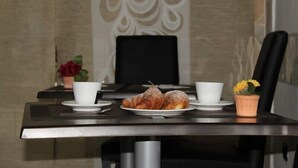 A dining table with croissants, two white cups, and a small potted plant. - Albergo della Posta (Genoa)
