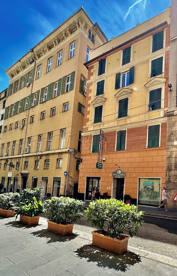 Un hôtel à plusieurs étages, doté d’une façade classique, de volets verts et d’une enseigne indiquant qu’il s’agit d’un hôtel.