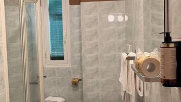 Un baño con ducha, inodoro, lavabo y ventana.