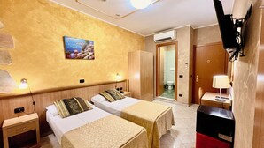 A hotel room with two beds, a desk, a TV, and an air conditioning unit. - Albergo della Posta (Genoa)