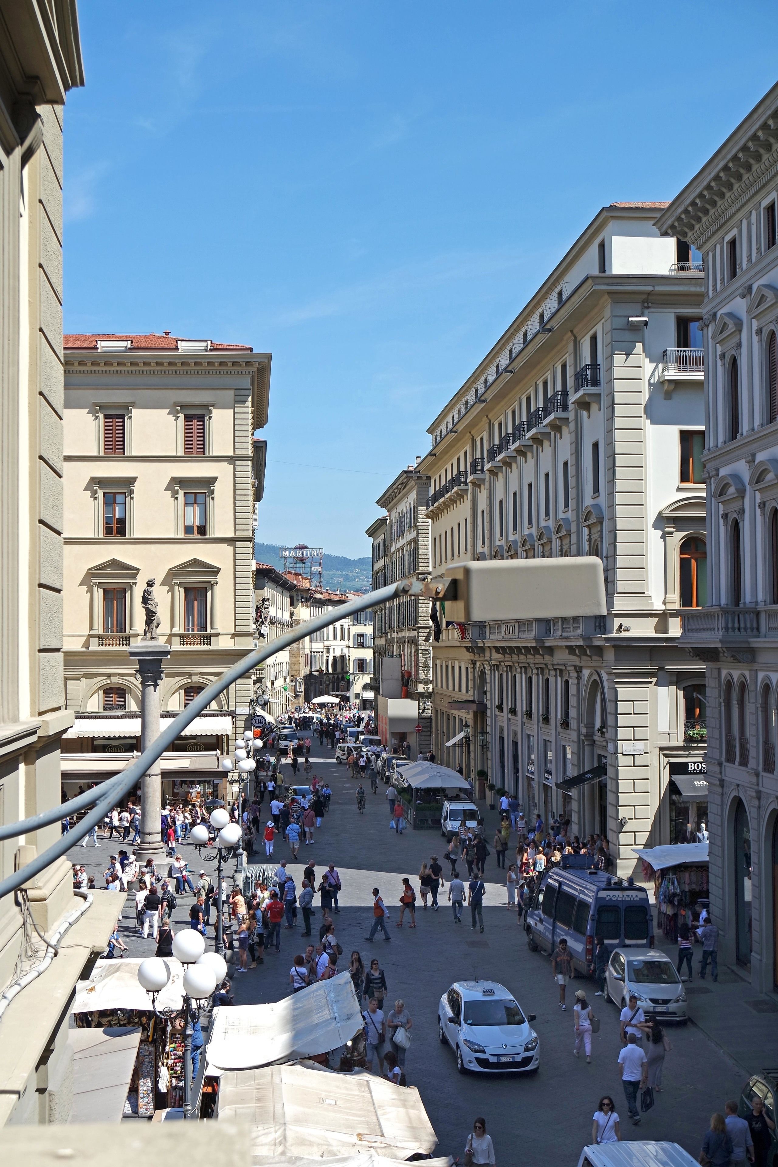 Une rue animée en plein centre-ville, bordée de bâtiments historiques, où l’on croise des piétons et des vendeurs à la sauvette.