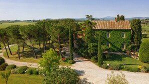 A house with a tiled roof, surrounded by a well-maintained garden and trees. - Casa Bellavista (Cortona)