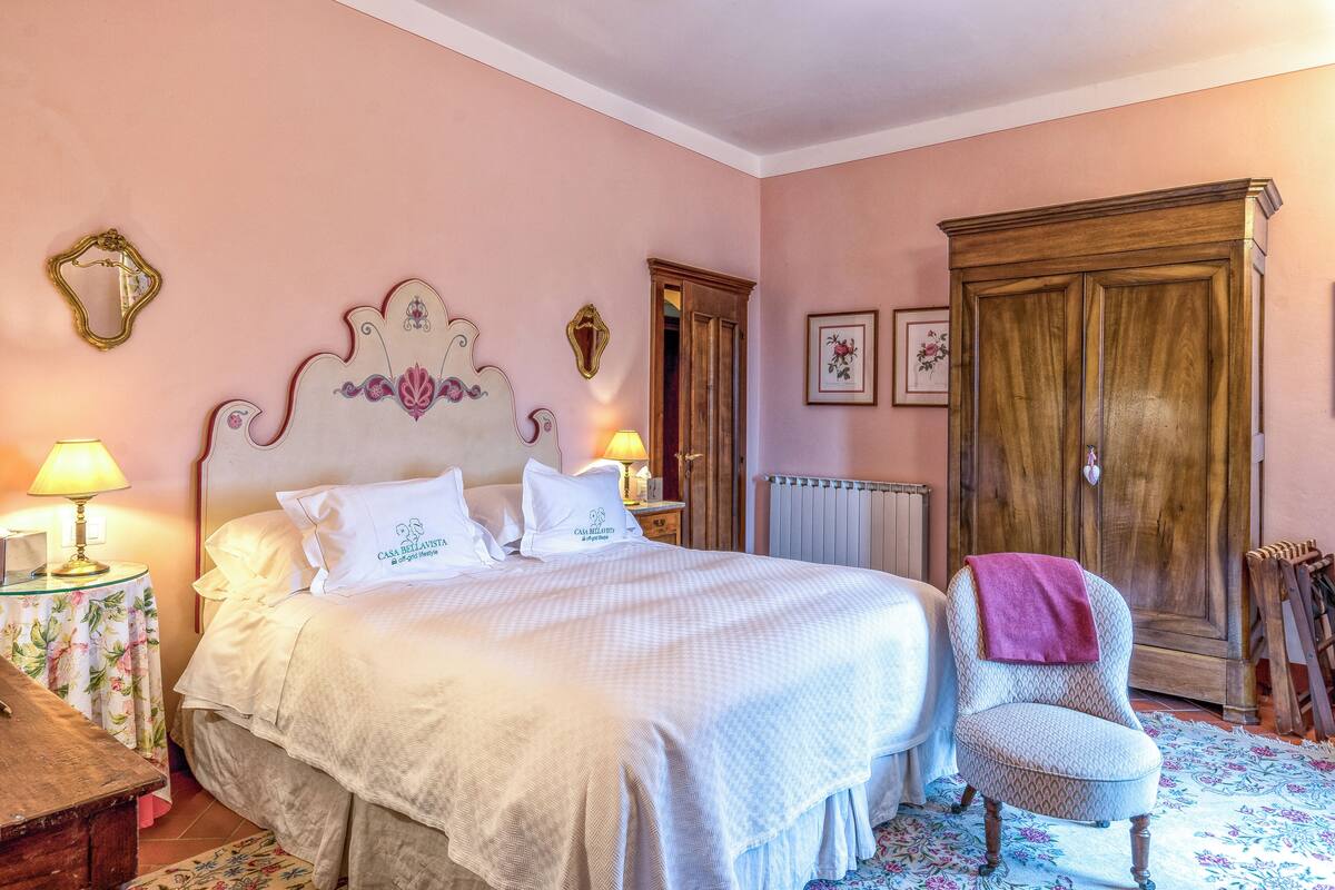 A bedroom with a bed, bedside tables, a chair, a wardrobe, and a radiator.
