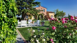 A traditional villa with a garden, outdoor seating, and a clear blue sky. - Casa Bellavista (Cortona)
