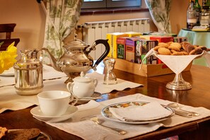 A breakfast table set with a teapot, cups, plates, and a basket of pastries. - Casa Bellavista (Cortona)