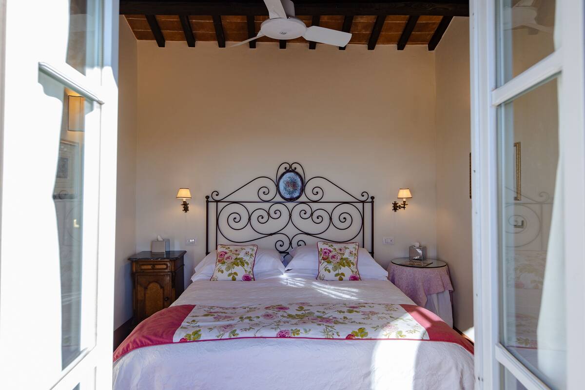 A bedroom with a bed, two bedside tables, a ceiling fan, and a window.