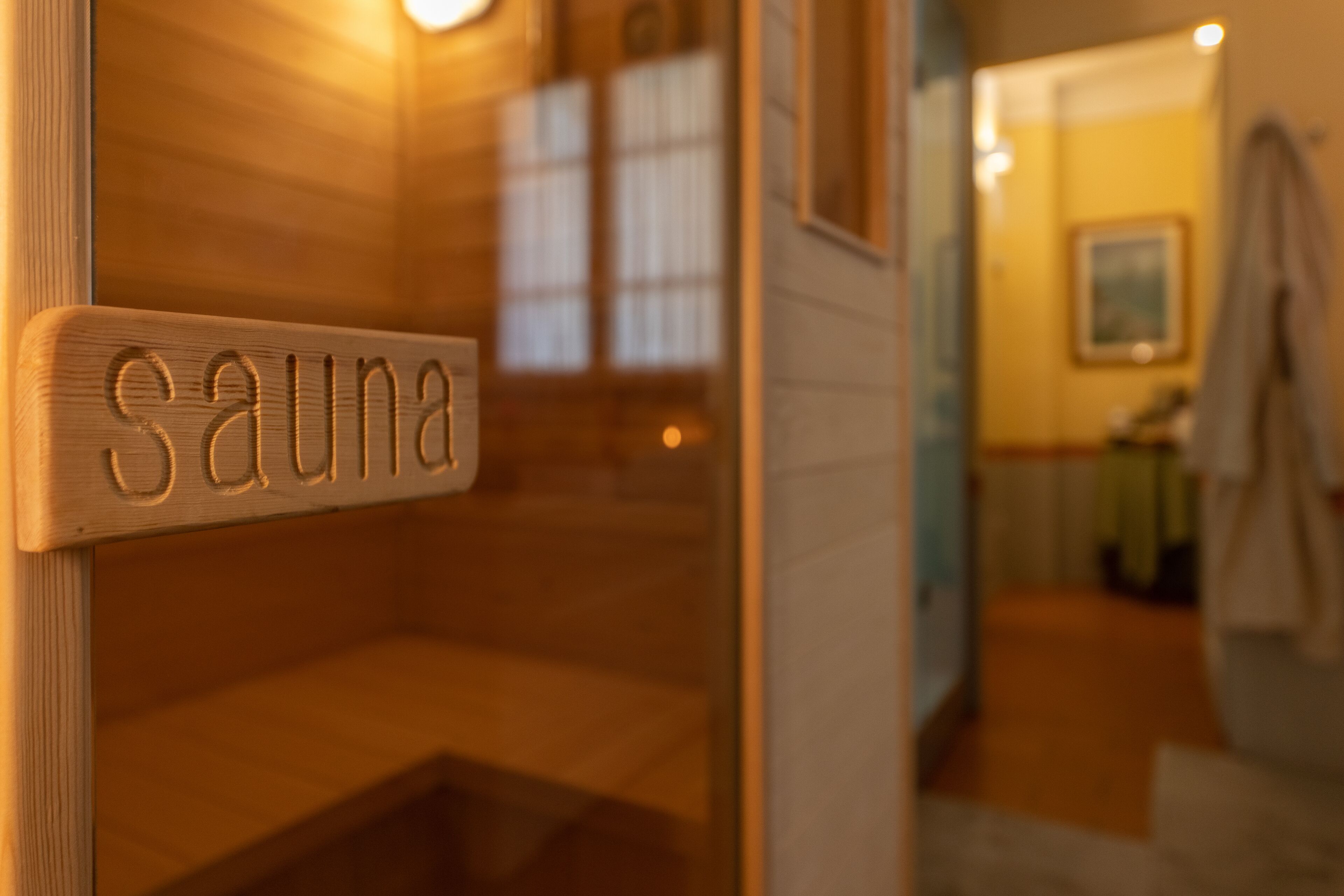 Une pancarte en bois portant le mot « sauna » indique l’emplacement du sauna.