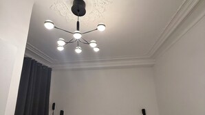 A room with two beds, a ceiling light fixture, and a wall-mounted telephone.