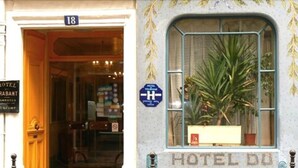 A hotel entrance with a sign indicating room number 18, a visible plant inside the window, and a blue sign with a white 'H' symbol.