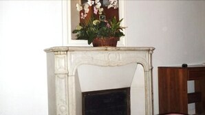 A white marble fireplace with a floral arrangement on top.