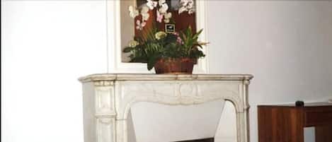 A white marble fireplace with a floral arrangement on top.
