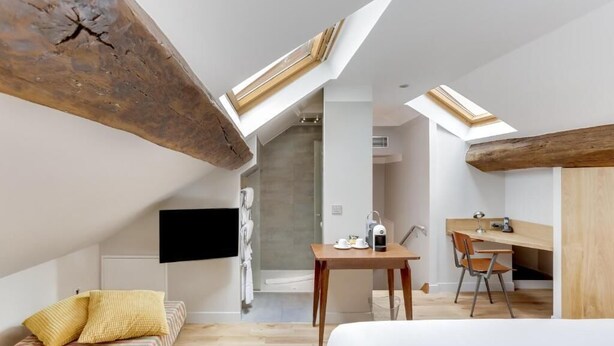A modern loft bedroom with skylights, a wooden desk, and a bed. - Hôtel Louvre Richelieu (Paris)