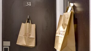 A door with the number 34, a keycard reader, and two paper bags hanging on the door. - Hôtel Louvre Richelieu (Paris)