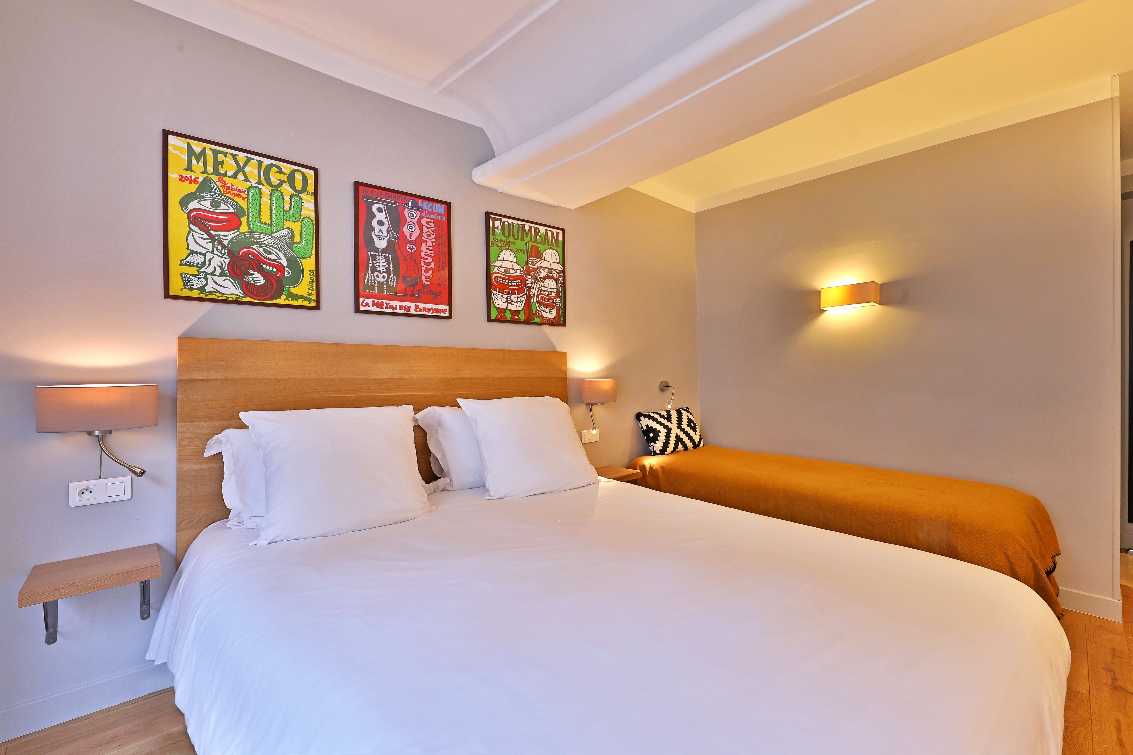 Une chambre d’hôtel avec un grand lit, deux lampes de chevet et trois œuvres d’art accrochées au mur.