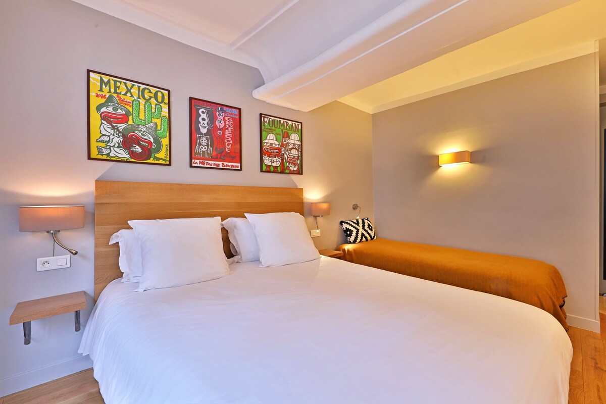 Una habitación de hotel con una cama grande, un cabecero de madera y tres carteles enmarcados en la pared.