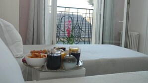 Bandeja de café da manhã com comida e bebidas sobre uma mesa em quarto de hotel com vista para uma varanda.