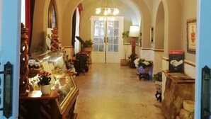 A hallway with arched ceilings, a chandelier, and a display case with items. - Xabier (Javier)