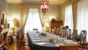 A formal dining room with a long table set for a meal, surrounded by wooden chairs. - Xabier (Javier)