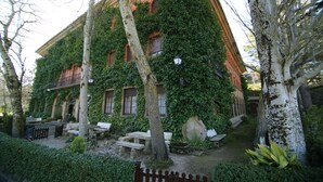 A building with ivy-covered walls and a courtyard with benches and a fountain. - Xabier (Javier)