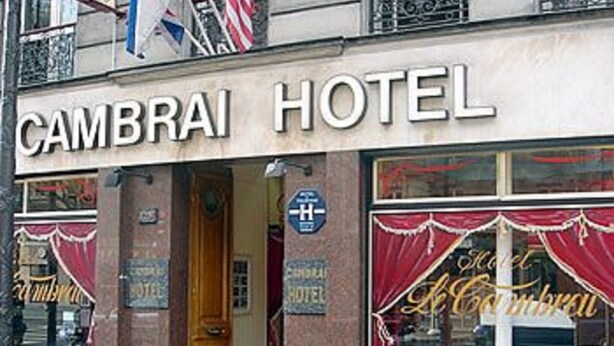 Het uiterlijk van Hotel Cambray, met een bord, deur en raamdecoraties.
